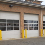 Yellow plastic bollard covers and bollards guarding a fire station's garage doors