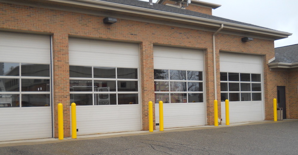 Yellow plastic bollard covers and bollards guarding a fire station's garage doors