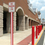 Red and white U-Channel Cover on a No Parking Fire Lane sign with red bollard covers in the background