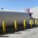 Large yellow plastic Bollard Covers guarding large propane tank