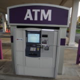 Clean ATM guarded by purple dome topped bollard covers