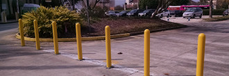 Yellow plastic dome top bollard covers sleeved over removable bollards